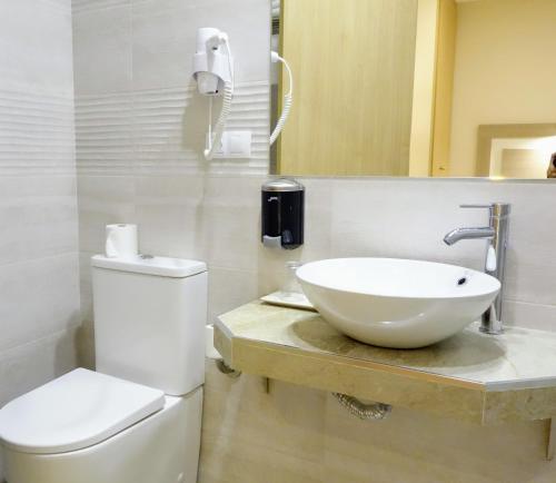 La salle de bains blanche est pourvue d'un lavabo et de toilettes. dans l'établissement Hostal Toledo, à Tolède