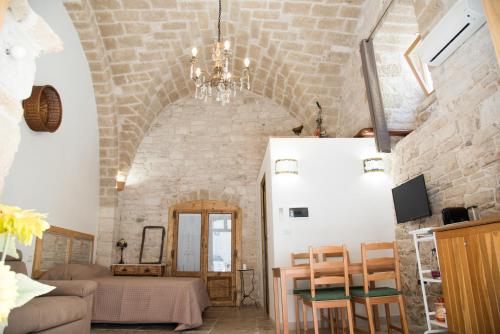 salon z kamienną ścianą i żyrandolem w obiekcie Piazza Duomo - Medieval Puglia's House w mieście Giovinazzo