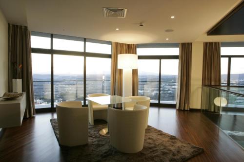 a living room with a table and chairs and windows at Montebelo Viseu Congress Hotel & Spa in Viseu