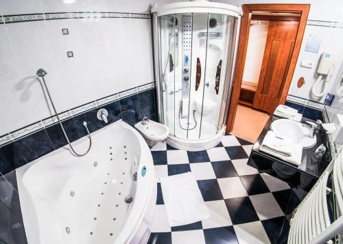 a bathroom with a tub and a shower and a sink at Hotel Silver in Hajdúszoboszló