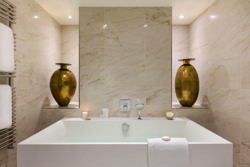 a bathroom with a tub and two vases on the wall at Hôtel Barrière L'Hermitage in La Baule