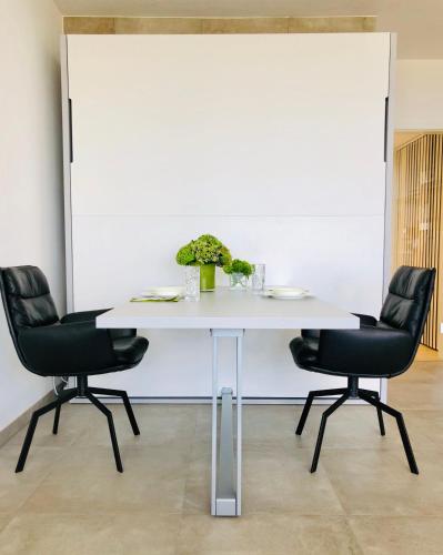a white table with two chairs and a white wall at Blue City Apartments in Lübeck