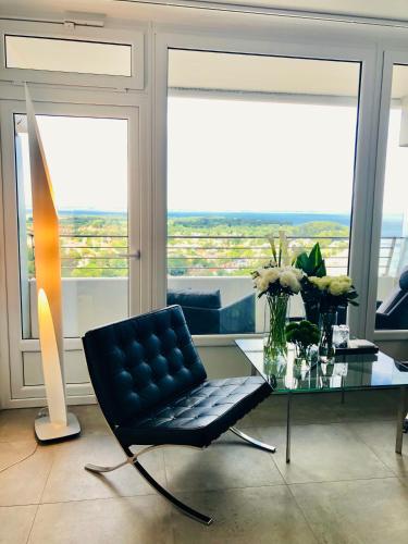 a living room with a black chair and a glass table at Blue City Apartments in Lübeck