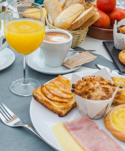 a table topped with plates of food and a glass of orange juice at Aparthotel Nelva Resort in Cala'n Porter