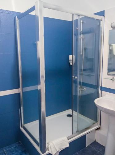a glass shower in a blue bathroom with a sink at Hotel Villa Natali in Chişinău