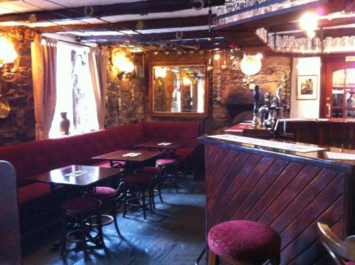 un restaurant avec un canapé rouge, des tables et des chaises dans l'établissement The Cross Keys Hotel, à New Galloway