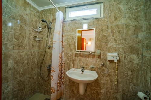ein Bad mit einem Waschbecken und einer Dusche mit einem Spiegel in der Unterkunft Belek Akropolis Medusa Otel in Belek