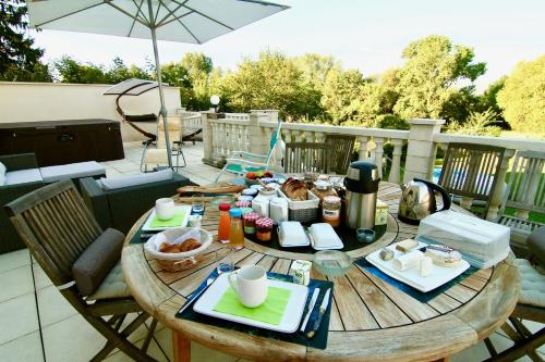a wooden table with food on a patio with an umbrella at La Lambertine & Spa in Saumur