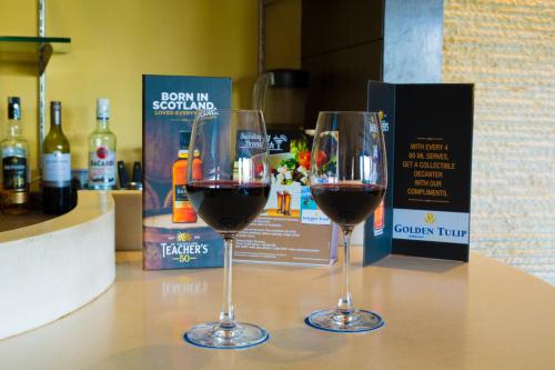 two glasses of red wine sitting on a table at Golden Tulip Chandigarh, Panchkula in Chandīgarh