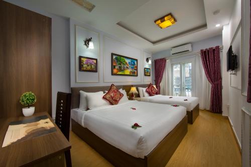 a hotel room with two beds and a table at Hanoi City Gate Hotel in Hanoi