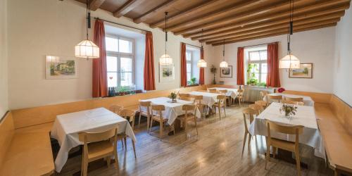 un restaurante con mesas y sillas blancas y ventanas en Haus Noldin - historische Herberge - dimora storica, en Salorno