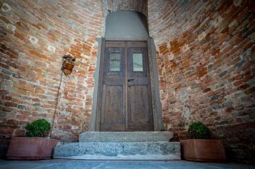 a wooden door in a brick building with two plants at La Canonica - charming self-catering apartments in Nizza Monferrato in Nizza Monferrato