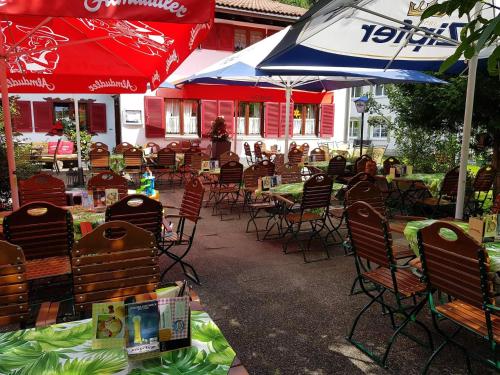 a group of chairs and tables with umbrellas on a patio at Gasthaus Pension Montafonerhüsli in Sankt Gallenkirch