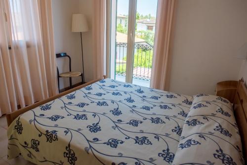 a bed with a blue and white comforter and a window at Riviera Residence in Marina di Pietrasanta