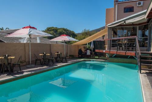 Una piscina con mesas y sillas al lado de un edificio. en Ramasibi Guest Services, en Panorama
