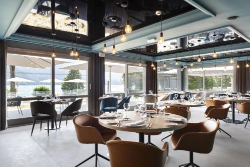 a restaurant with tables and chairs and large windows at Black Bass Hotel in Sévrier