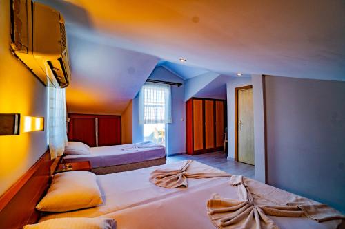 a bedroom with two beds and a tv on the wall at Belek Akropolis Medusa Otel in Belek