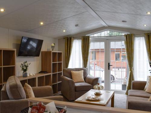 ein Wohnzimmer mit einem Sofa, Stühlen und einem TV in der Unterkunft Craigrossie lodge33 in Auchterarder