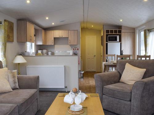 a living room with two couches and a kitchen at Craigrossie lodge33 in Auchterarder