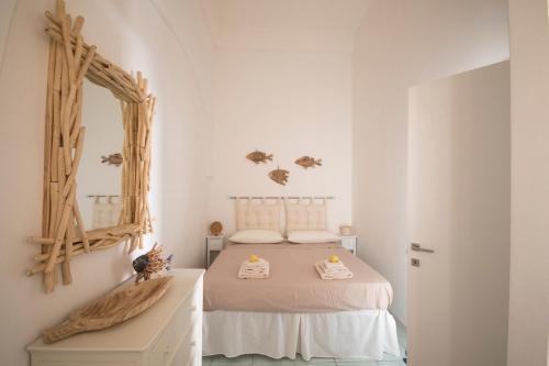 um quarto branco com uma cama e um espelho em Il mare di fronte “Casa Smeraldo” em Savelletri di Fasano