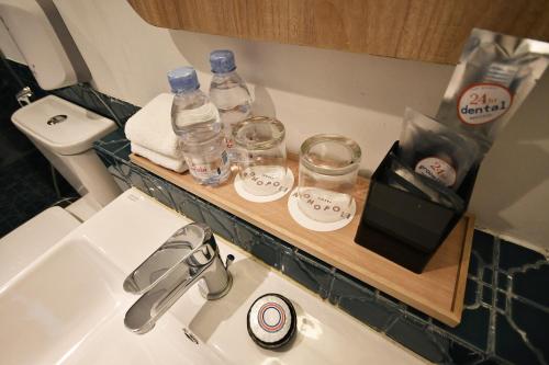a bathroom with a sink and a counter with water bottles and glasses at Hotel Monopoli in Jakarta
