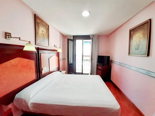 um quarto com uma cama branca e uma janela em Hosteria Sara by gaiarooms em Salamanca