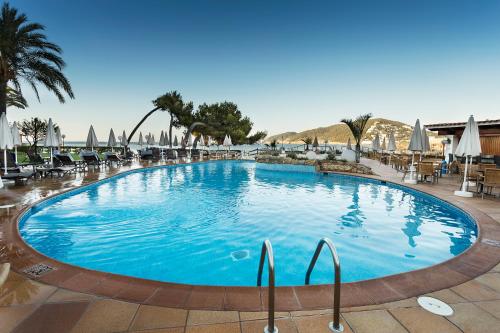 a large blue swimming pool with chairs and umbrellas at Catalonia Ses Estaques - Adults Only in Santa Eularia des Riu