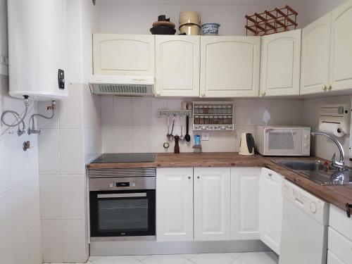 a white kitchen with white cabinets and appliances at Penthouse with panoramic view in Vilamoura