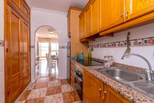 una cocina con armarios de madera y fregadero en Best House Rubi, en Playas de Orihuela