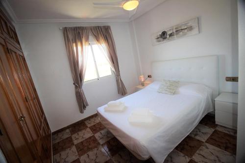 sypialnia z białym łóżkiem i oknem w obiekcie Best House Rubi w mieście Playas de Orihuela