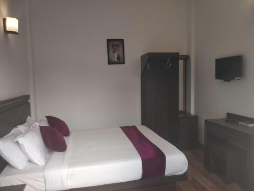 a bedroom with a bed with pillows and a television at Landy Queen in Munnar