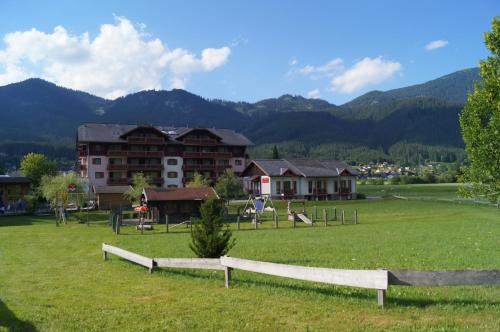 a large grassy field with houses and mountains in the background at Hallstatt Dachstein Inn in Gosau