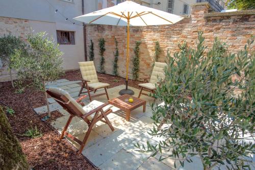 a patio with two chairs and an umbrella at La Canonica - charming self-catering apartments in Nizza Monferrato in Nizza Monferrato