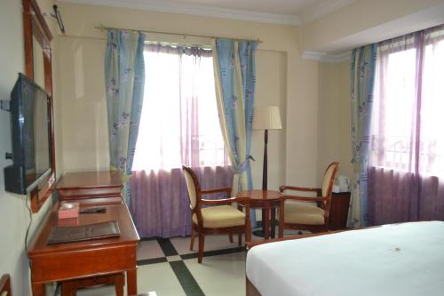 a hotel room with a bed and a desk and chairs at Hotel Nikko Towers in Dar es Salaam