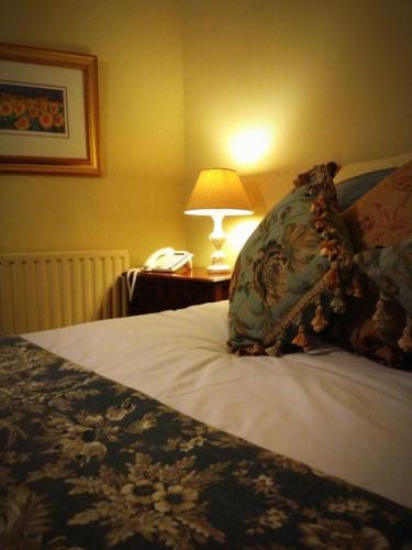 a bed with a pillow and a lamp on a table at Softleys in Market Bosworth