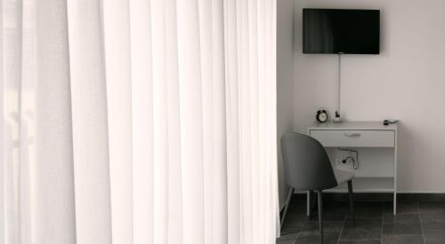 a room with a desk and a television and a curtain at Filipovic rent a car & apartments in Selnica Šćitarjevska