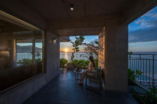 a woman sitting on a balcony watching the sunset at Chicland Danang Beach Hotel in Danang