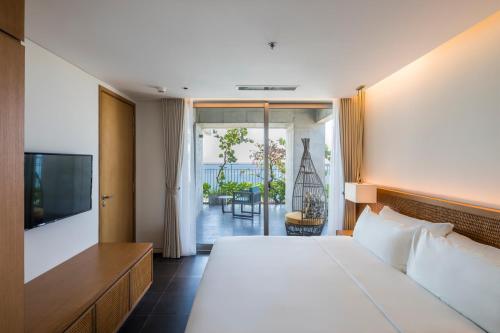 a bedroom with a bed and a television and a balcony at Chicland Boutique Danang Beach Hotel in Da Nang