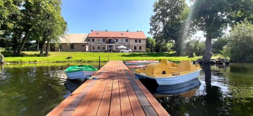 un muelle con barcos sobre el agua frente a una casa en Zajazd Zamkowy - Schloßgasthof, en Krąg