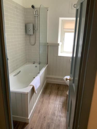 a white bathroom with a tub and a window at The Swan and Talbot in Wetherby