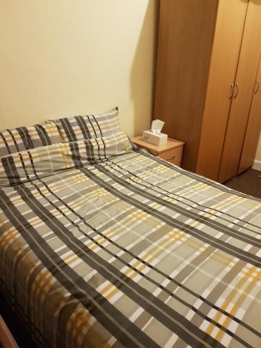 - un lit avec une couette rayée dans une chambre dans l'établissement Family Rest At Best Location with Best Price, à Londres