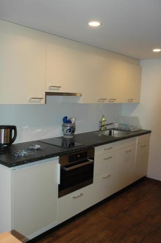a kitchen with white cabinets and a black counter top at Ferienwohnung Uf dr Liwwi in Grindelwald
