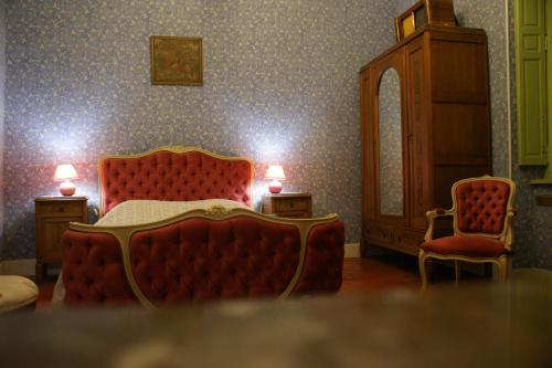 a bedroom with a red bed and a chair at Maison du Parc in Saint-Chinian