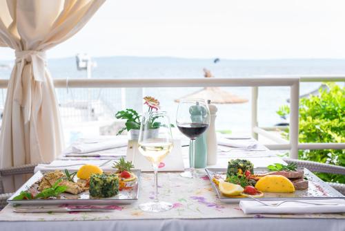 a table with a plate of food and a glass of wine at Hotel Maritimo in Makarska