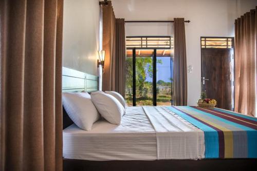 a bedroom with a large bed with a window at Wadula Safari - Yala in Kataragama