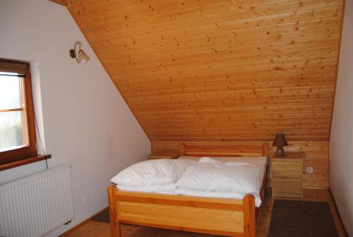a bed in a room with a wooden ceiling at Domek w Bartoszymlesie in Stara Kiszewa