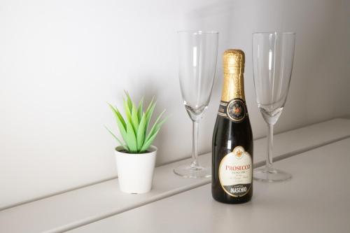 a bottle of champagne sitting on a shelf with two wine glasses at b&b Zio Luciano in Avola