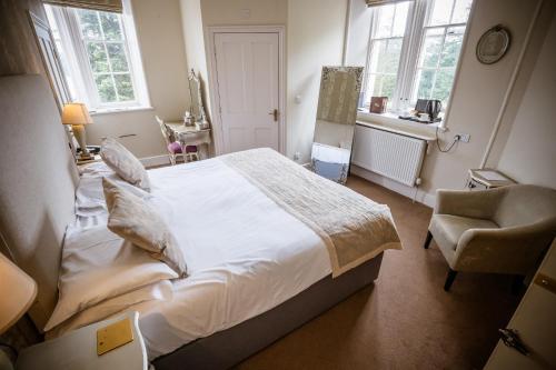a bedroom with a large white bed and a chair at Château Rhianfa in Menai Bridge