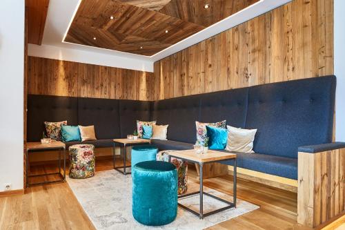 a room with a blue couch and two tables at Ferienhotel Jörglerhof in Hainzenberg