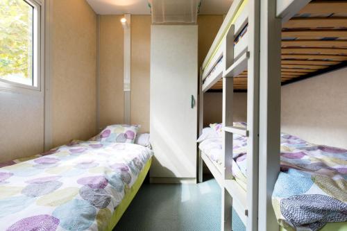 a bedroom with two bunk beds and a ladder at Camping Bungalows El Far in Calella